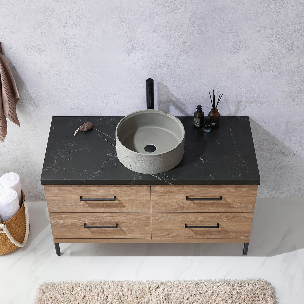 Stone top, a circular concrete vessel and the bar handles of the drawers below, seen head-on