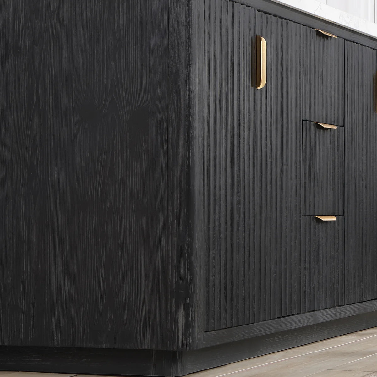 Corner of the freestanding vanity showing fluted panels, door and drawer fronts and a plinth base