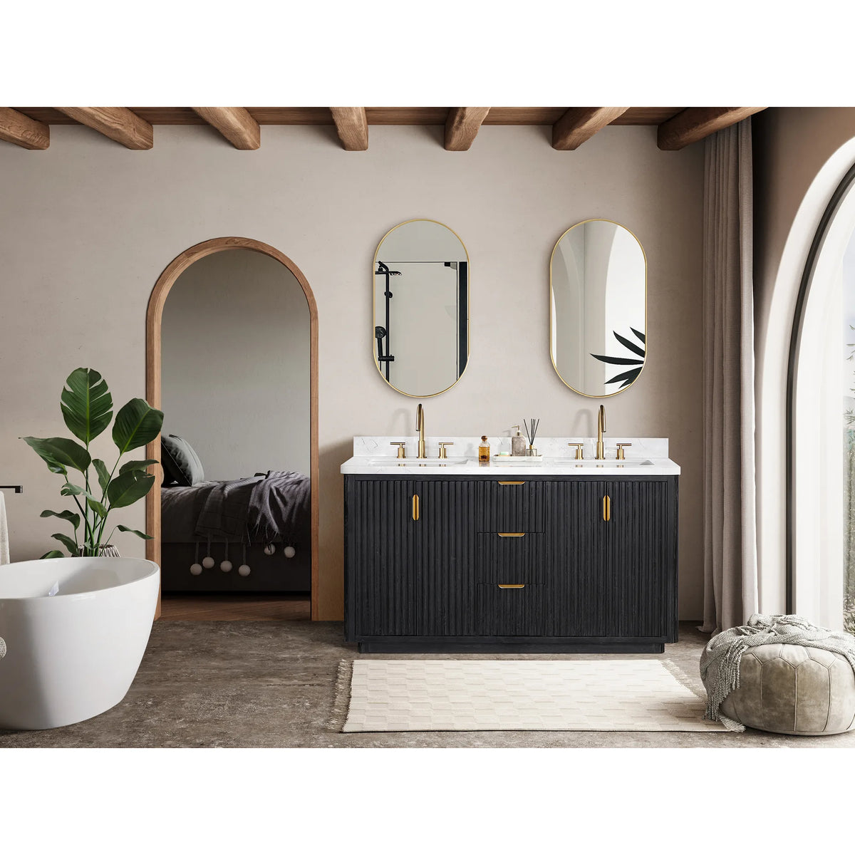 Wide view of the vanity below oval mirrors, arched openings behind and a bathtub at the left