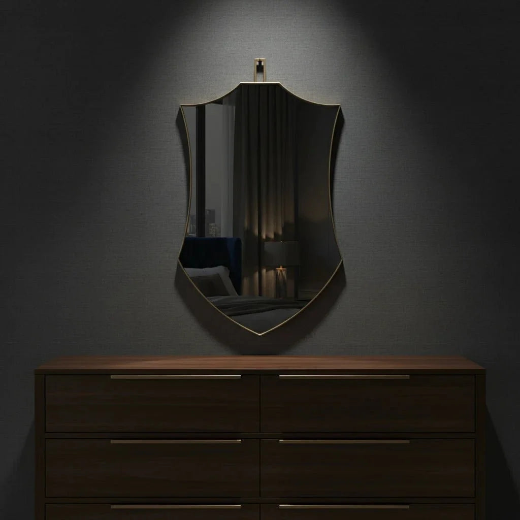 Decorative mirror with a dark frame on a gray wall above a wooden dresser.
