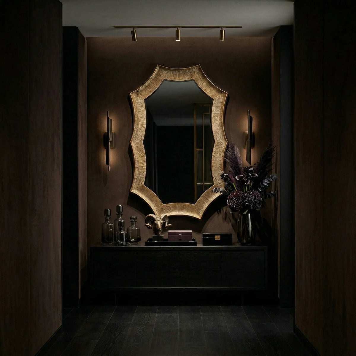 Helios Mirror Large by Ambella Home, decorative gold wall mirror with an irregular geometric silhouette, displayed above a modern console in a moody entryway with warm ambient lighting