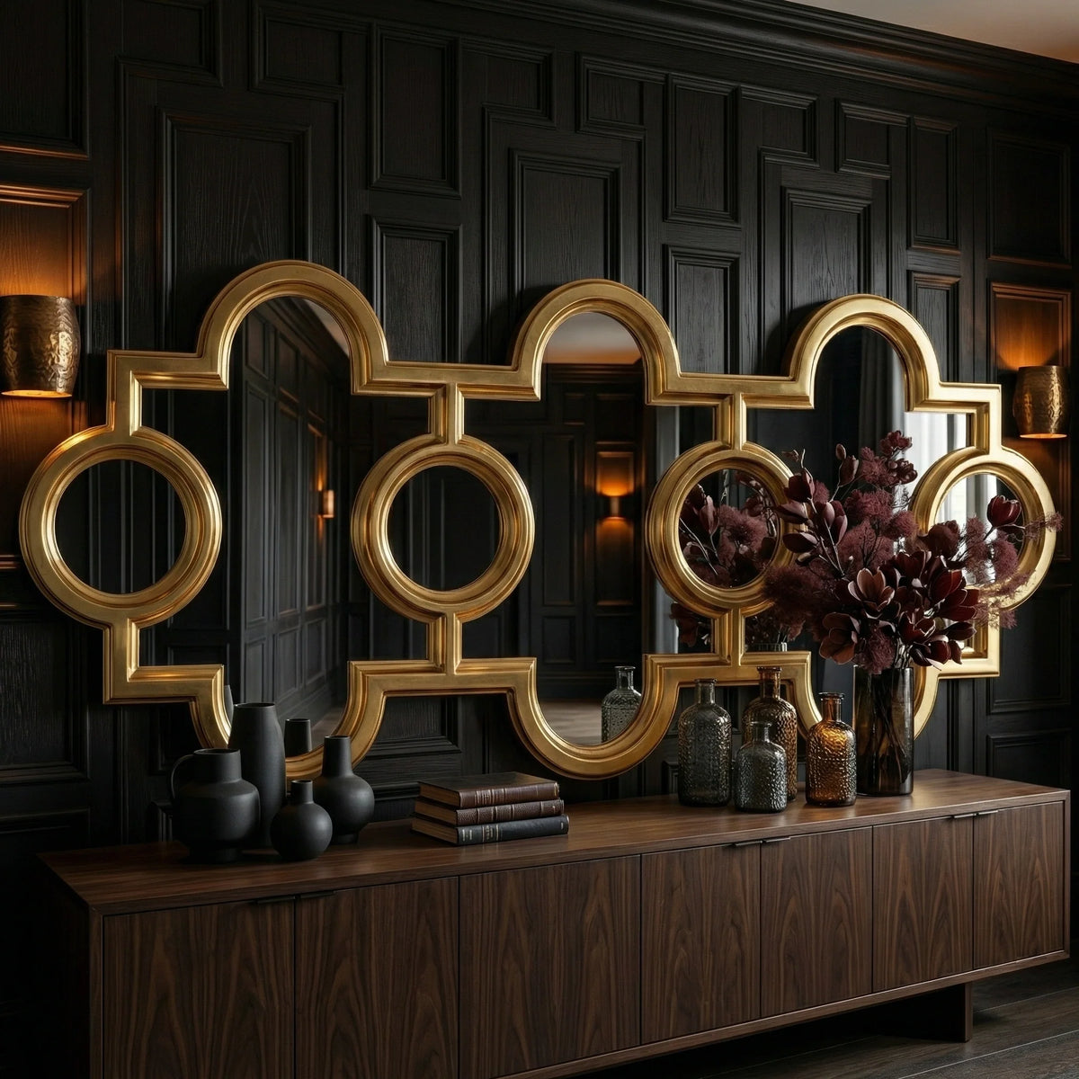 Oversized Voranado Mirror by Ambella Home in burnished gold leaf, 99 inch horizontal statement mirror with sculptural open-frame pattern above a wood console in a dark luxury interior hall