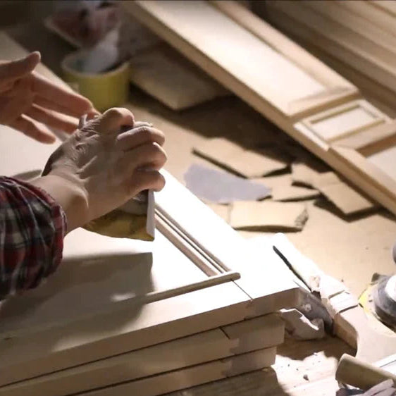 Person working with wood on a wooden table on vanity door with tools and materials.