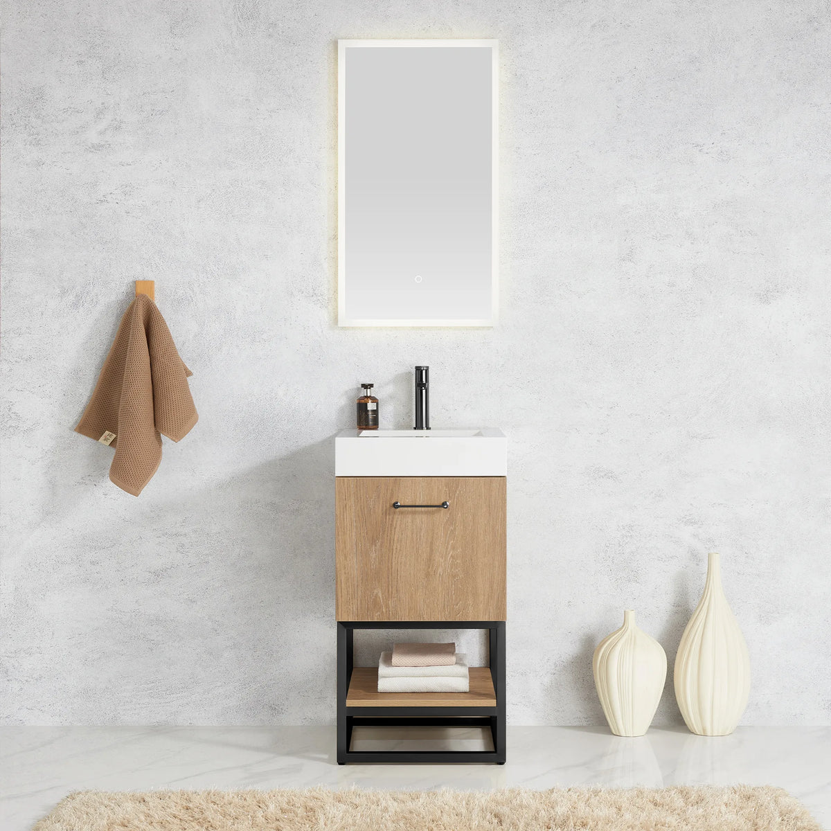 Room scene with the compact vanity under a wall mirror, brown towel on a hook and cream vases on the floor