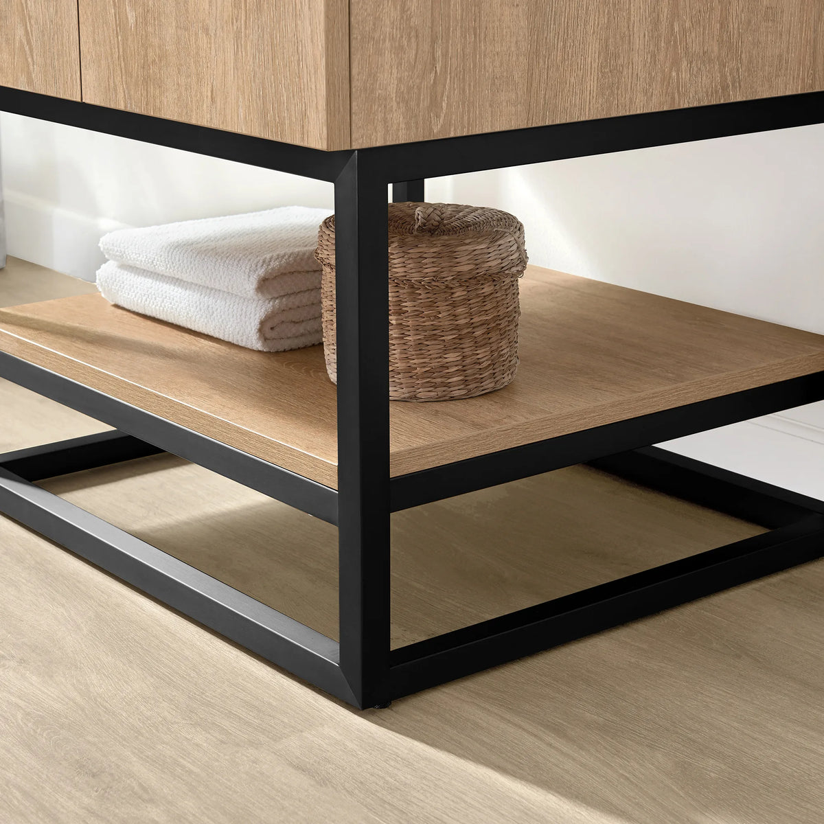 Close-up of the open shelf with towels and a basket inside the Matte Black metal base