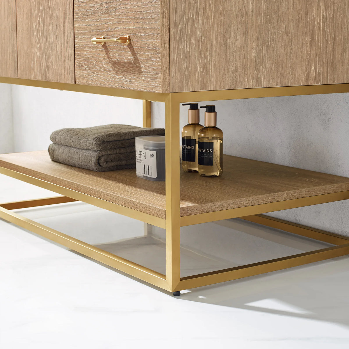 Detail of the open shelf with a folded towel and bottles inside the gold metal base