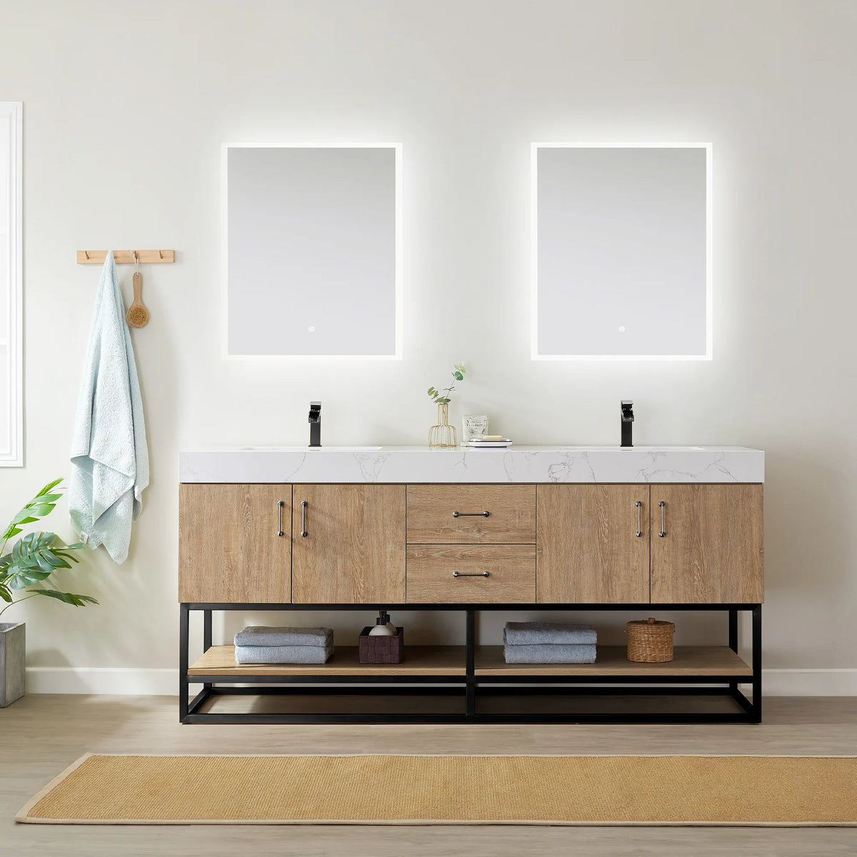 Centered room view of the double vanity under backlit mirrors, wall hooks, towel and baskets on the open shelf