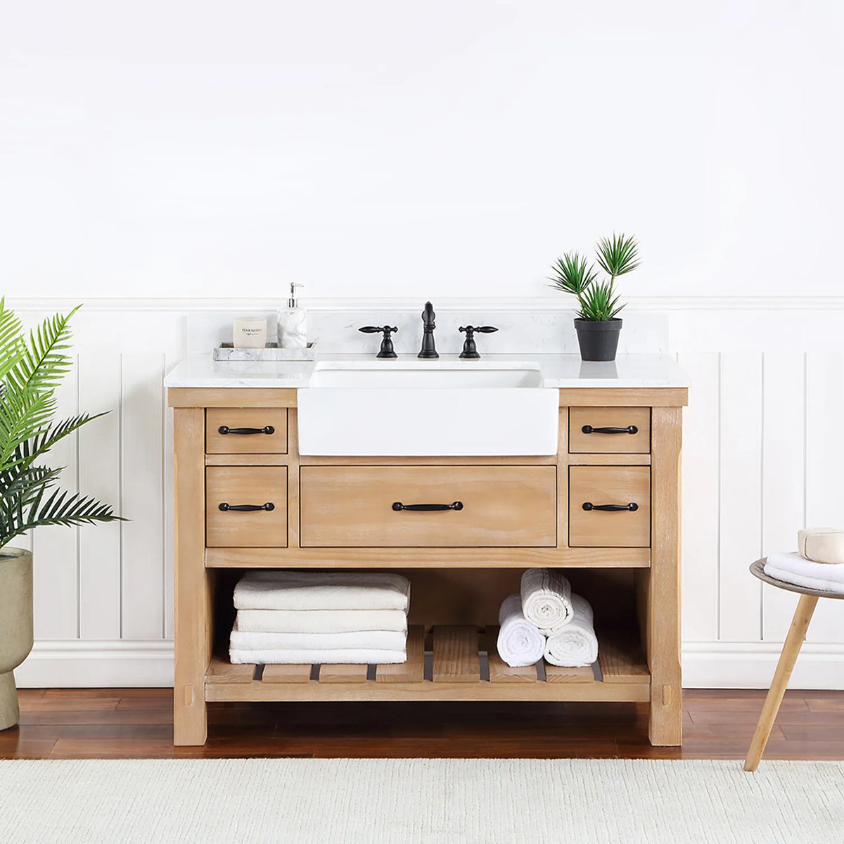 Bathroom setting with white paneled wall, fern and side table beside the vanity