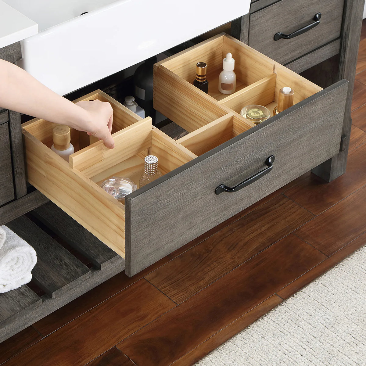 Hand adjusting wood dividers inside a pulled-out drawer