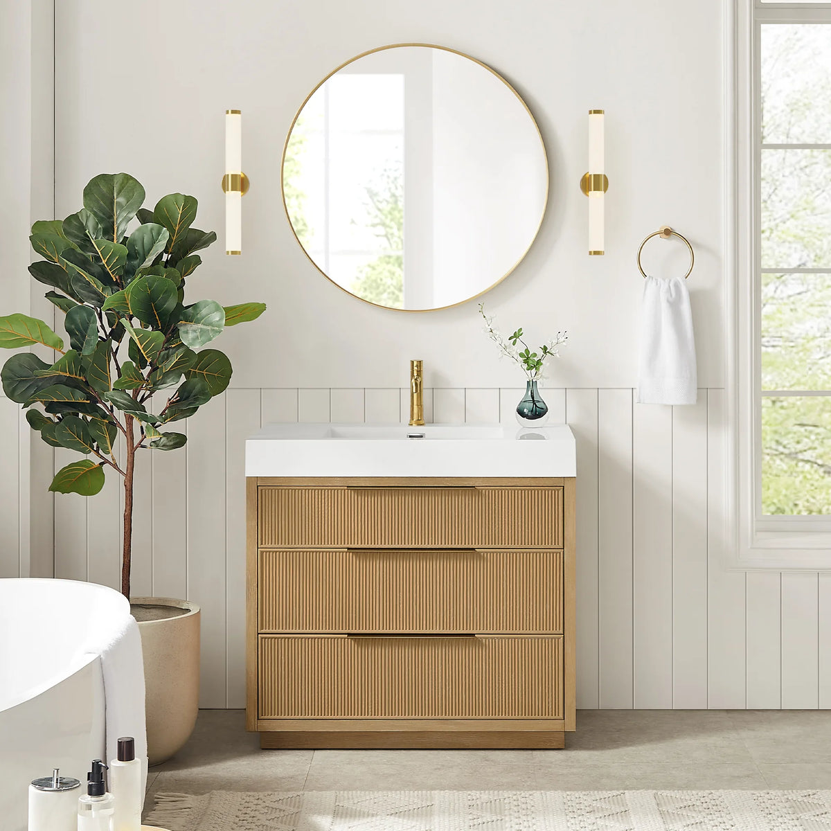 36-inch single vanity under a circular gold mirror flanked by wall sconces, with a tall plant and a towel ring beside it
