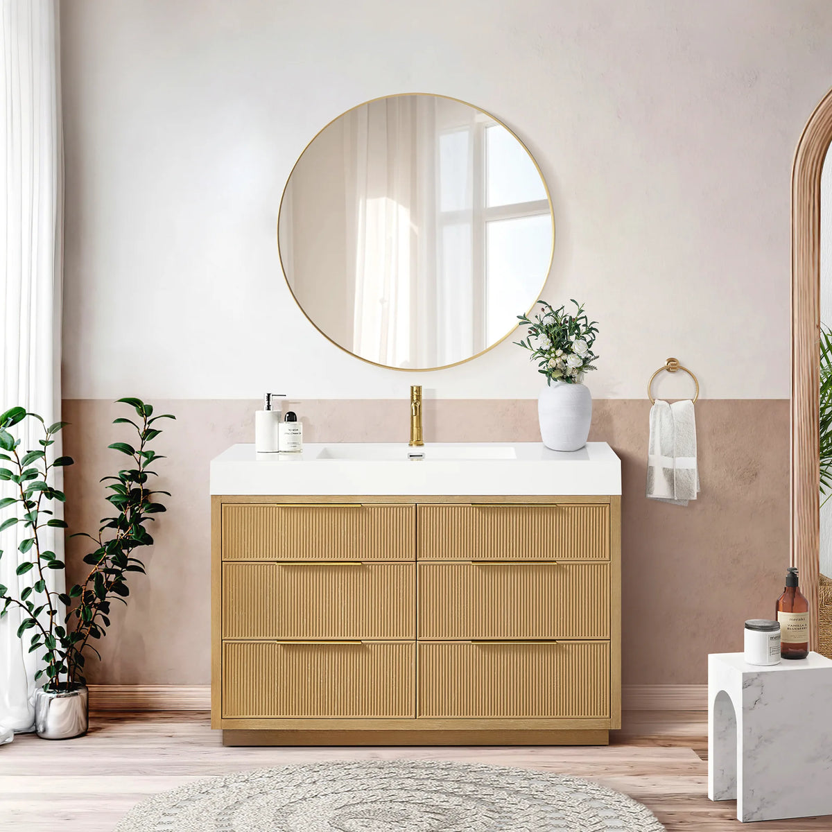 Room shot of the 48-inch single vanity with six drawer fronts and a circular gold mirror, plus a blush wall and stool
