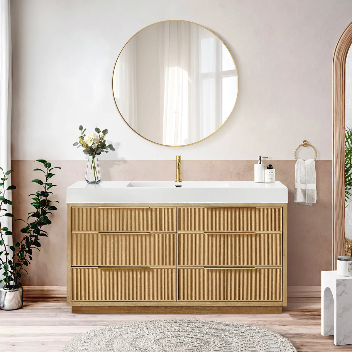 Room scene of the 60-inch single vanity with six ribbed drawers, a circular gold mirror, a blush wall and an arched niche
