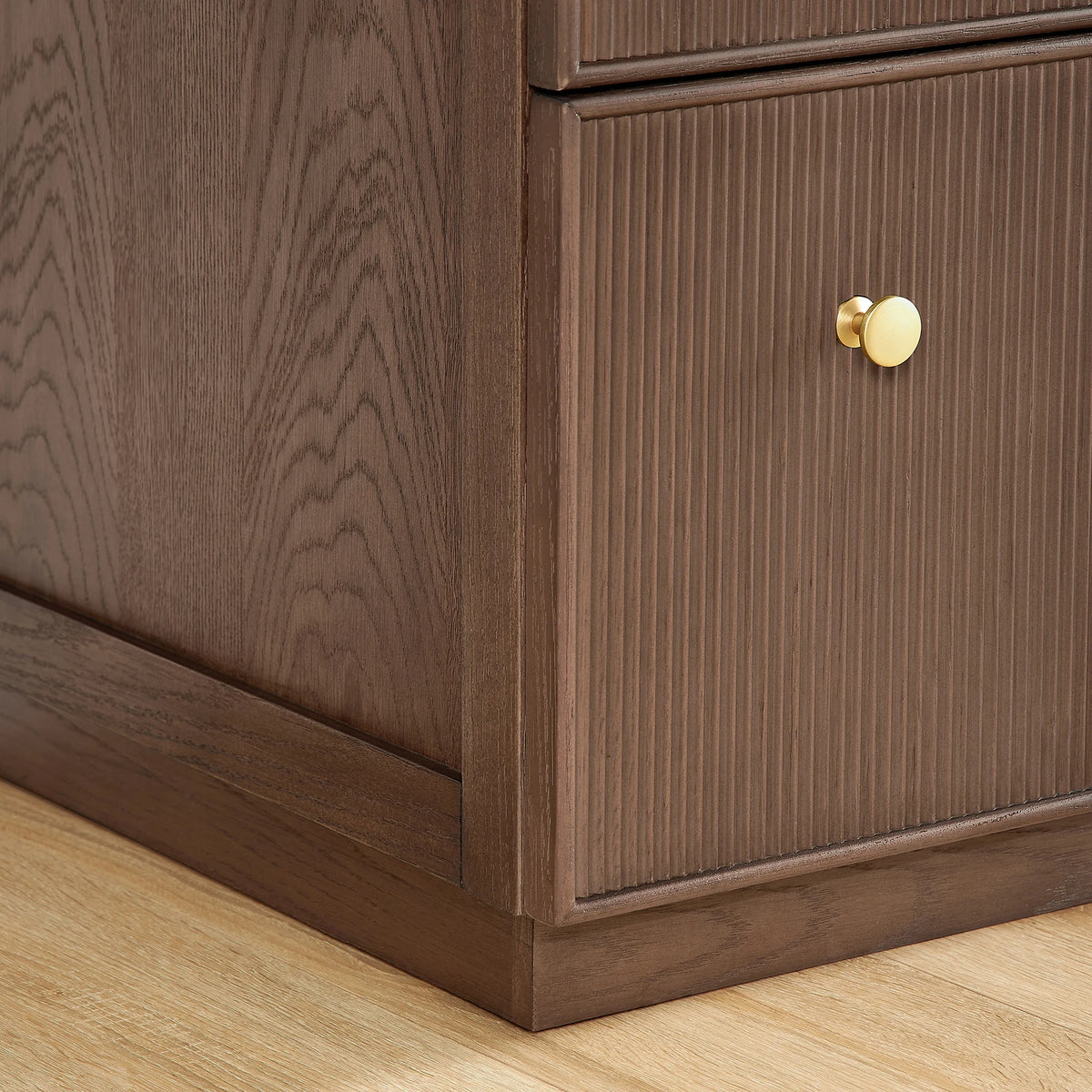 Close view of a textured door front, Brushed Gold handle and cabinet base in Aged Dark Brown Oak