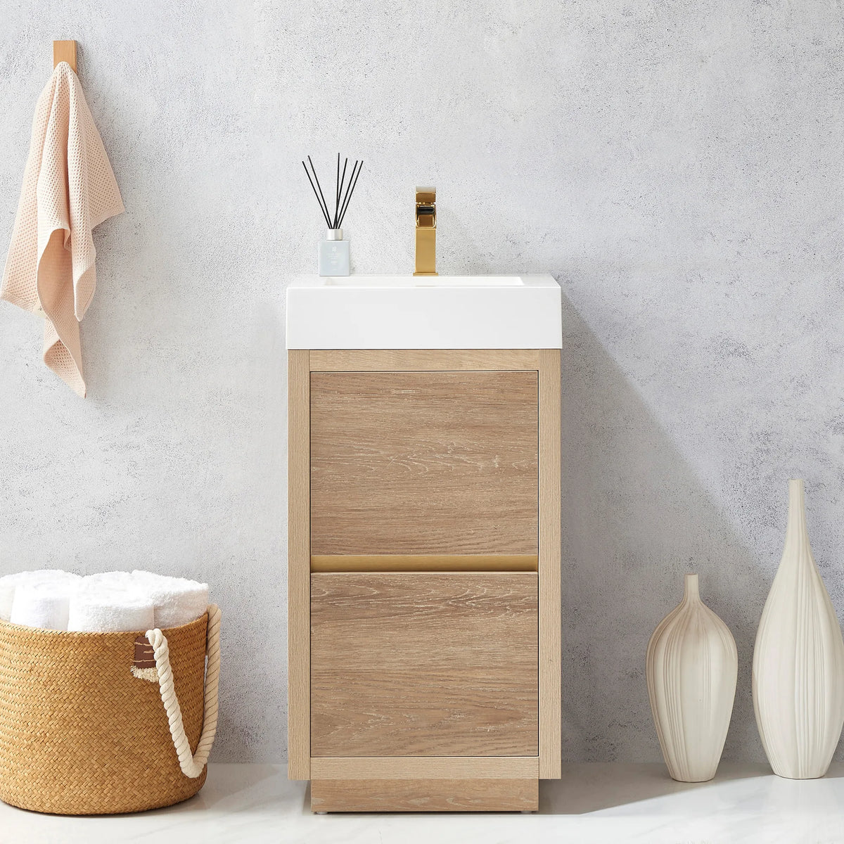 Close front view of the 18 inch vanity next to a towel basket and a tall white vase