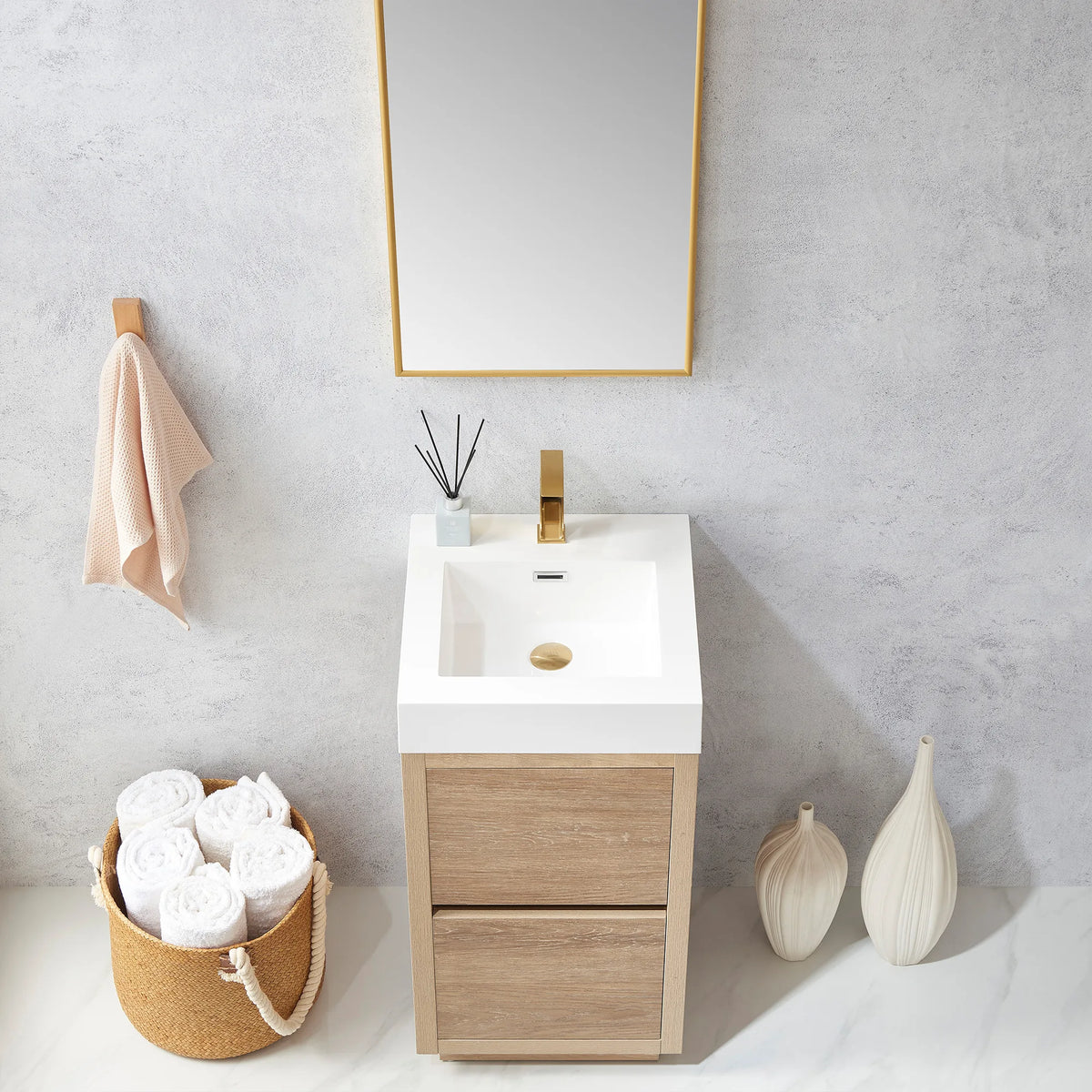 Medium shot of the vanity with mirror, towel hook and diffuser sticks, white basin in view