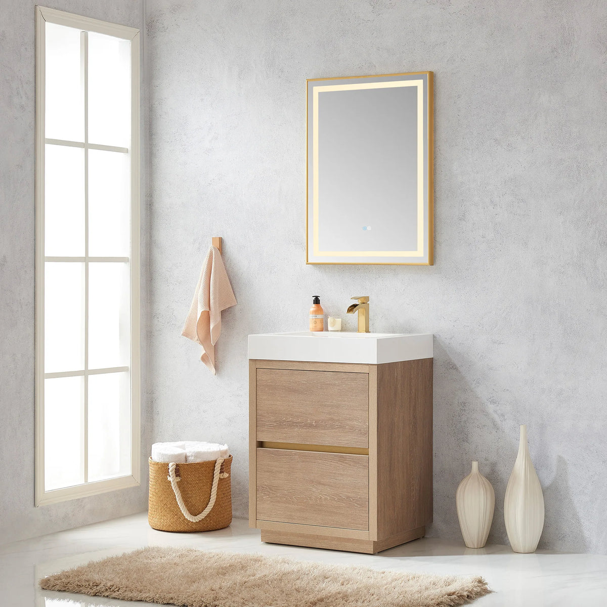 Wide room view of the 24 inch vanity with mirror, hook, basket of towels and white vases