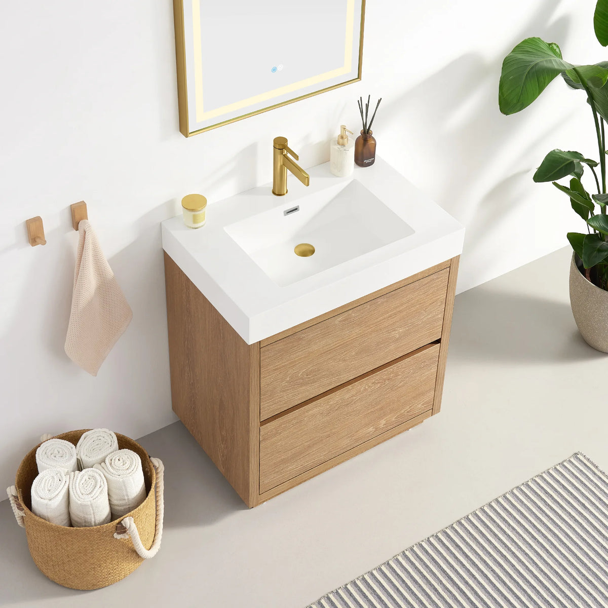 High-angle view of the vanity with mirror edge visible, towel basket at left and plant at right