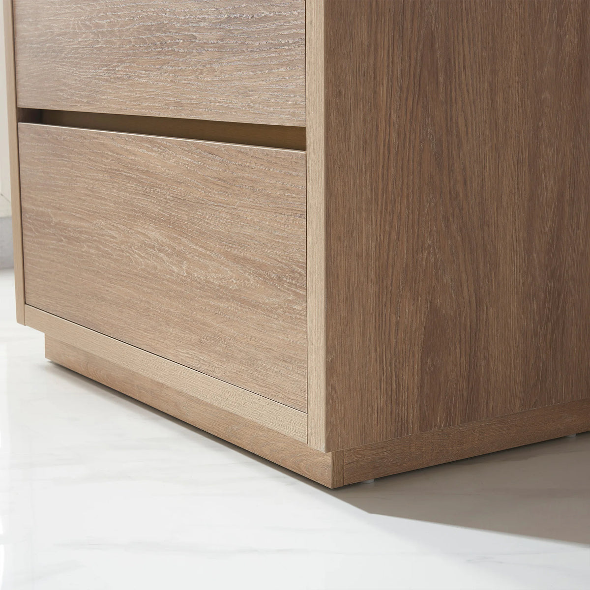 Close-up of the vanity side panel and base plinth, white tile floor