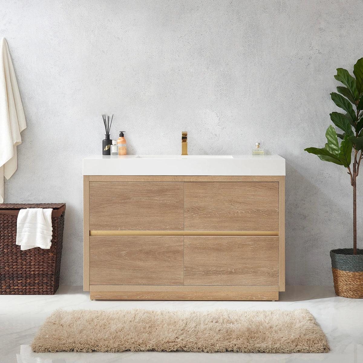 Medium shot of the vanity with diffuser and bottle on top, towel hamper at left and plant at right
