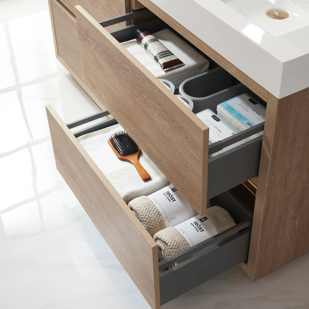 Close-up of open drawers with towels, a hairbrush and toiletries, oak fronts angled out
