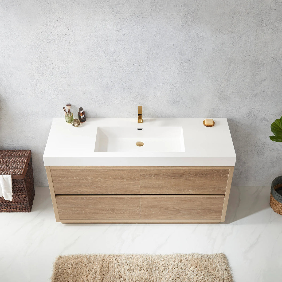 Top view of the white integrated sink with bottles at the back, hamper and rug in view