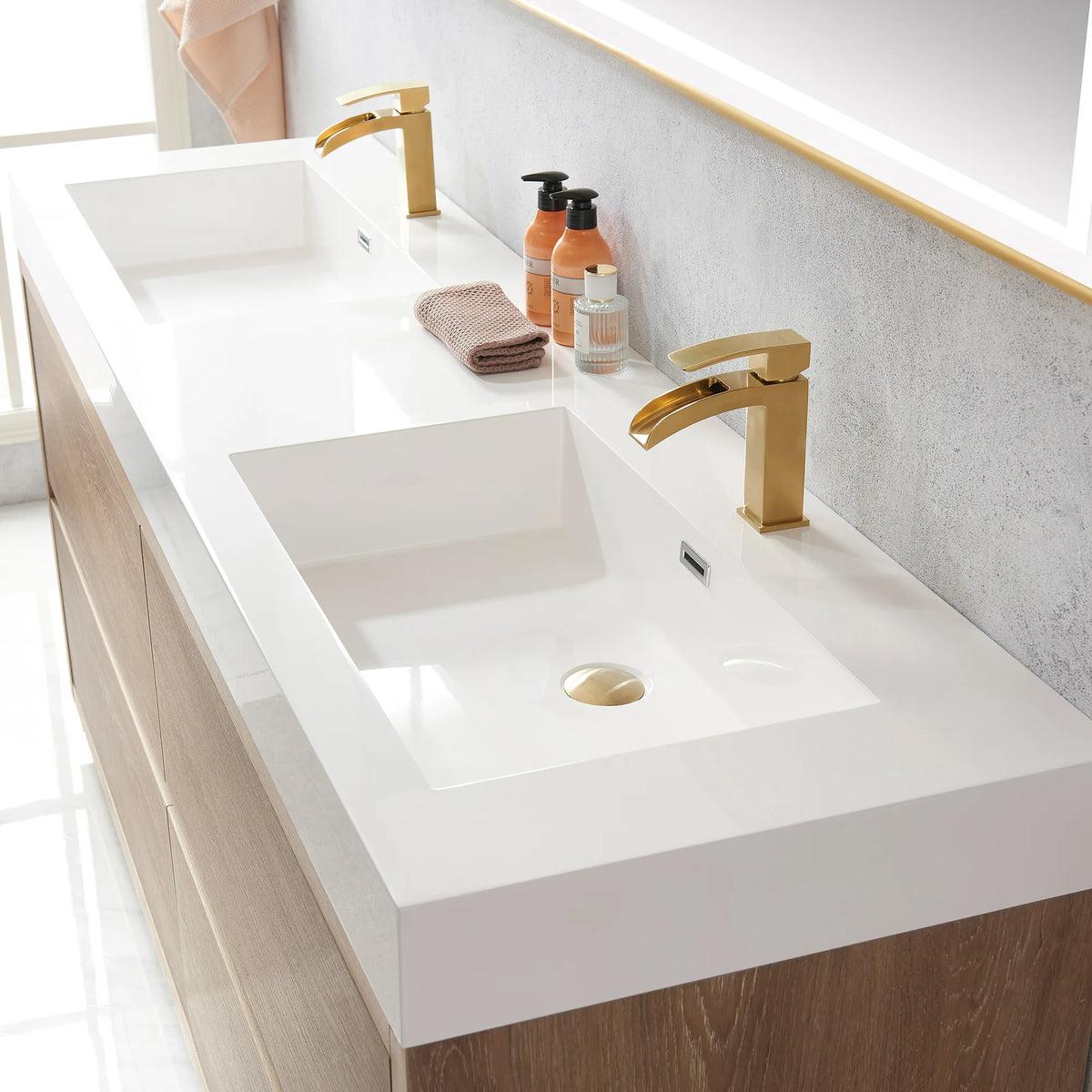 Close-up of the double sink top with drain and soap bottles, mirror edge at upper right
