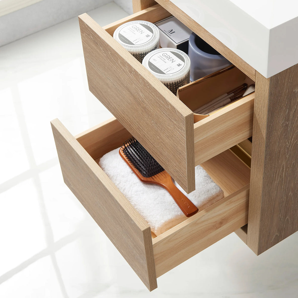 Looking into open drawers lined with a towel and holding small jars, white sink top above