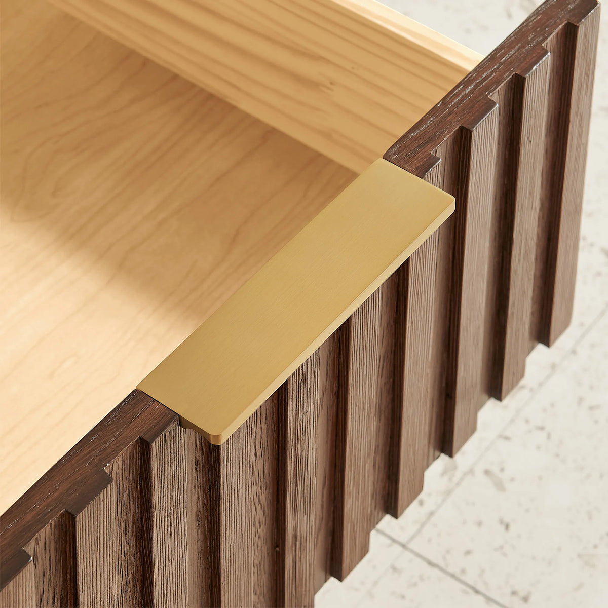 Macro view of a gold flat handle and ridged wood front on the 60-inch double vanity