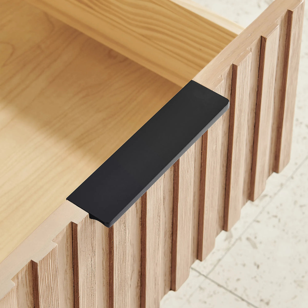 Macro view of a black flat handle and ridged wood front on the 60-inch double vanity