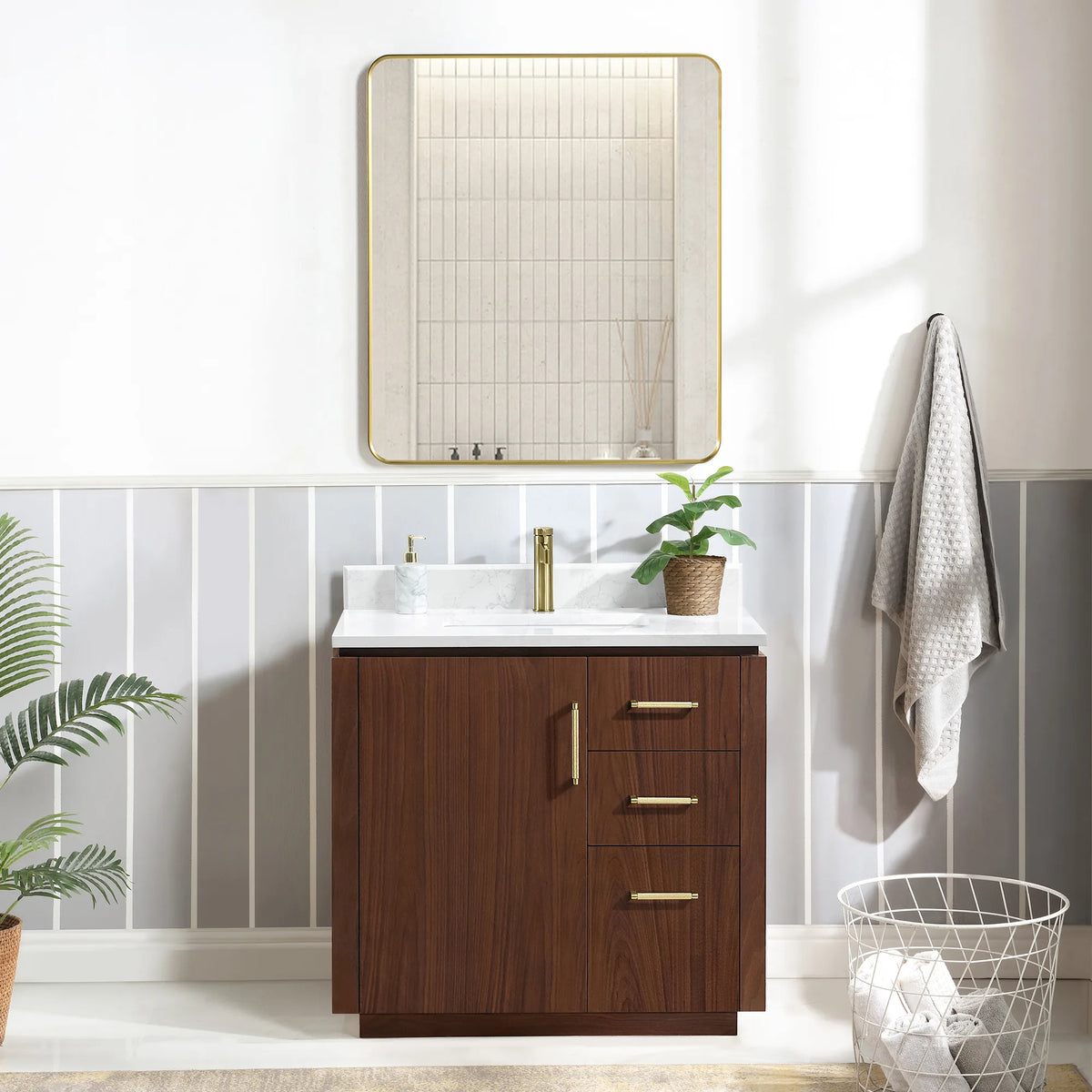 Room scene with a Natural Walnut vanity, framed mirror overhead, hanging towel, plant and wire basket on the floor