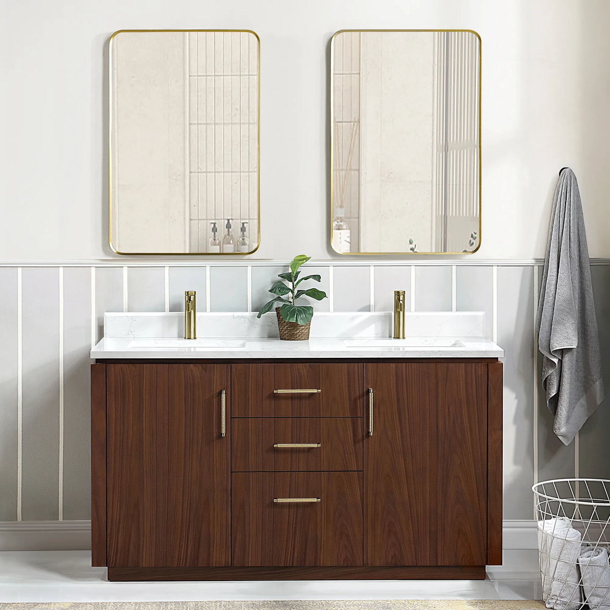 Wide room view of the double vanity with mirrors, a plant at center and a wire basket at the right