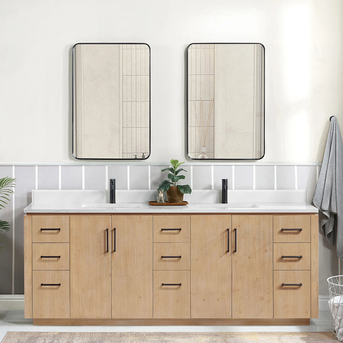 Room scene with the matching mirrors over the vanity, a hanging gray towel and a wire basket