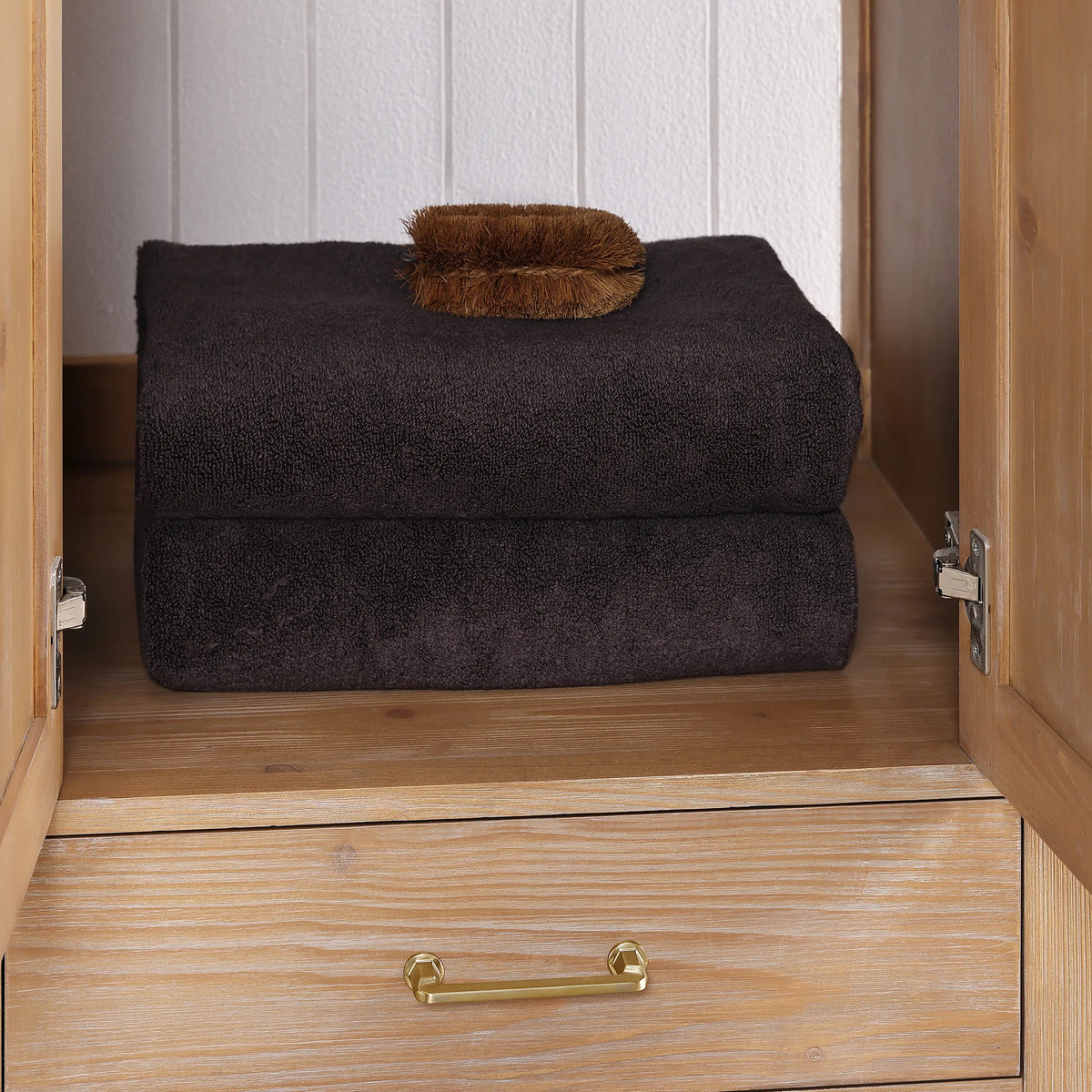 Open doors reveal a shelf with towels and a scrub brush