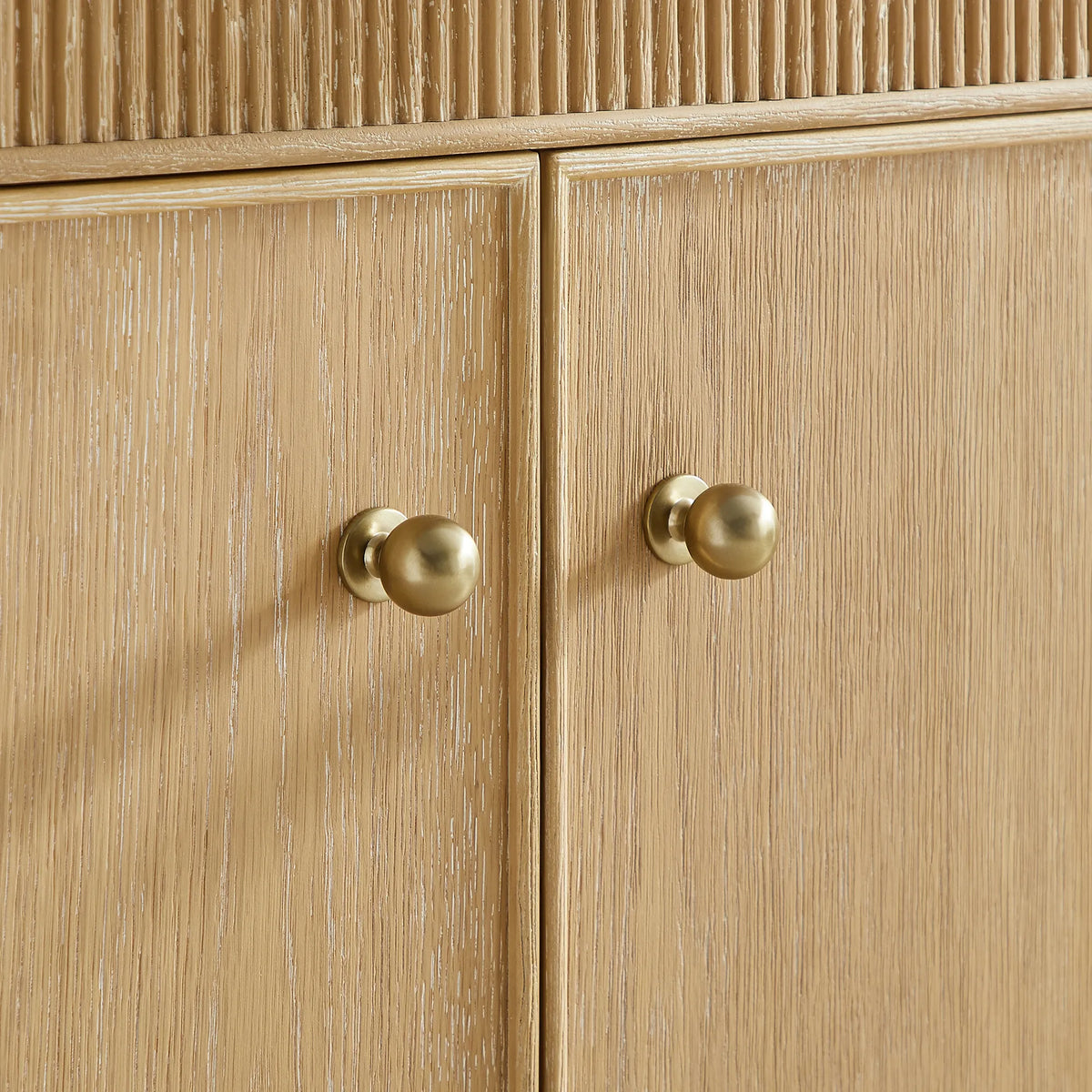 Gold ball knobs and wood grain on the Washed Ash Grey cabinet doors, tight crop