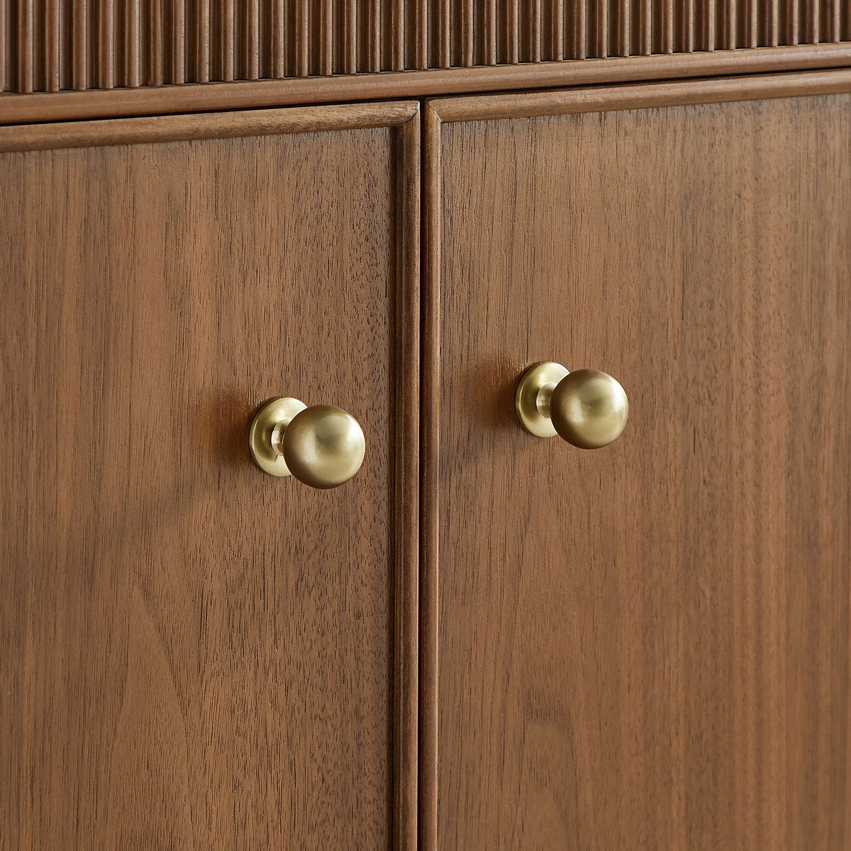 Gold ball knobs and wood grain on the Natural Walnut cabinet doors, tight crop