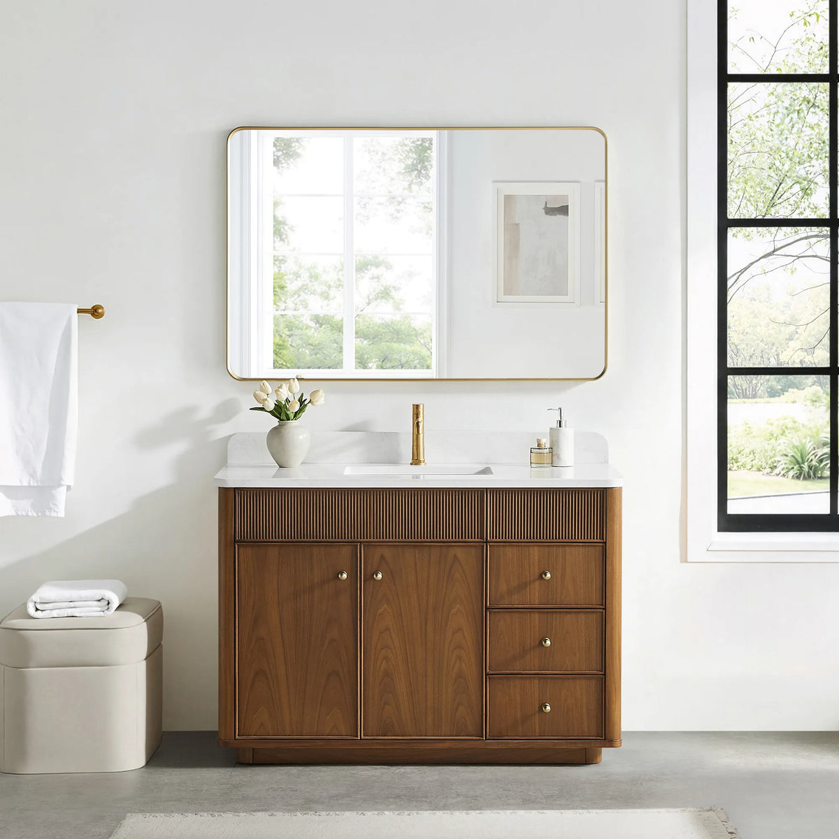 Matching wide rounded-rectangle gold mirror above the Natural Walnut vanity in a bathroom with a black-framed window