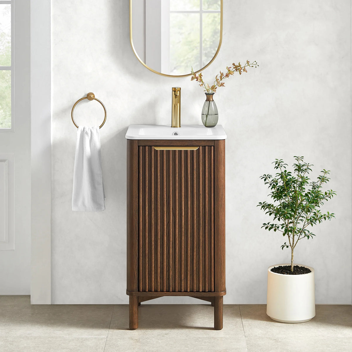 Small bathroom scene pairing the 18-inch vanity with its matching oval mirror, a potted plant and a hand towel on a ring