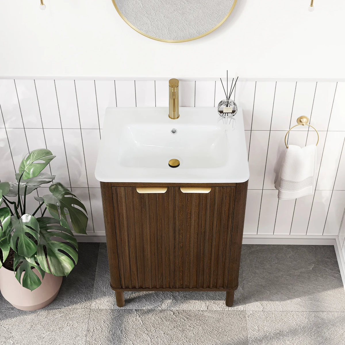 High view of the compact 24-inch single vanity over vertical white tile, a monstera plant at its side