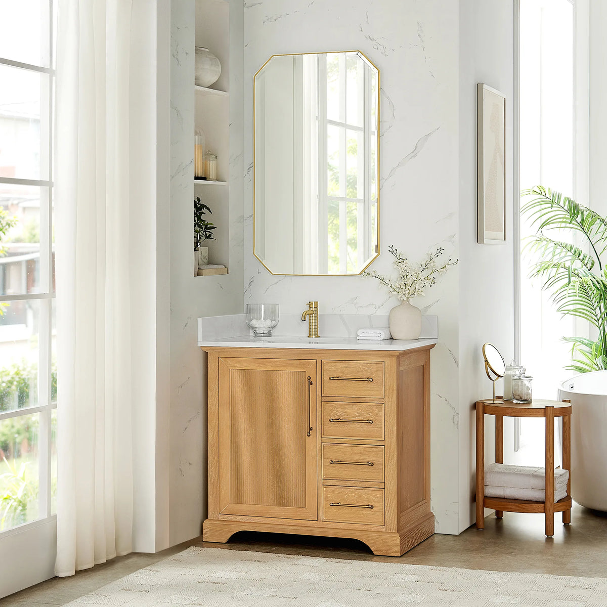 Room scene: Oak Natural Brown single vanity with an octagonal mirror above and a round wooden side table alongside