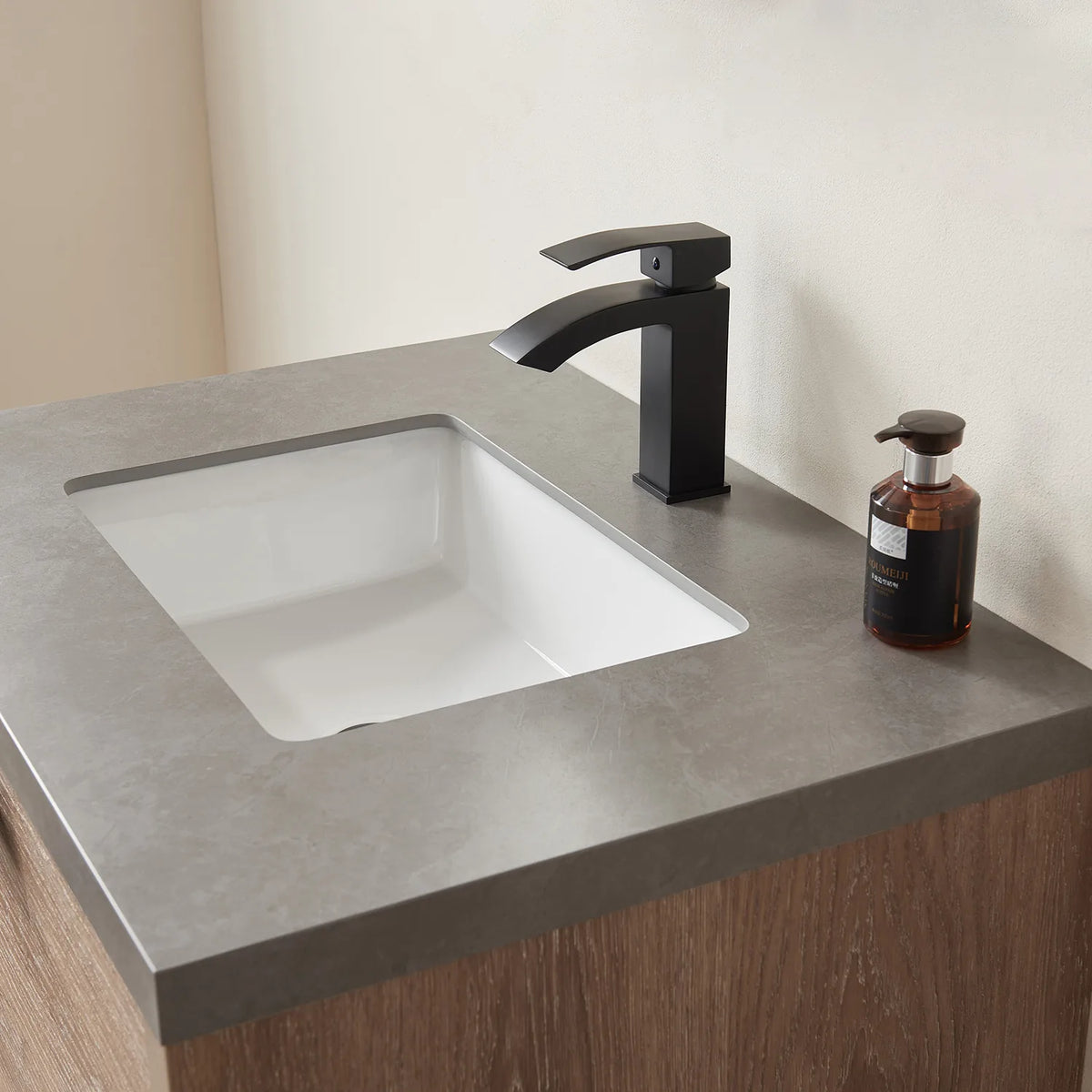 Black faucet and white rectangular basin on the stone top in an angled close crop