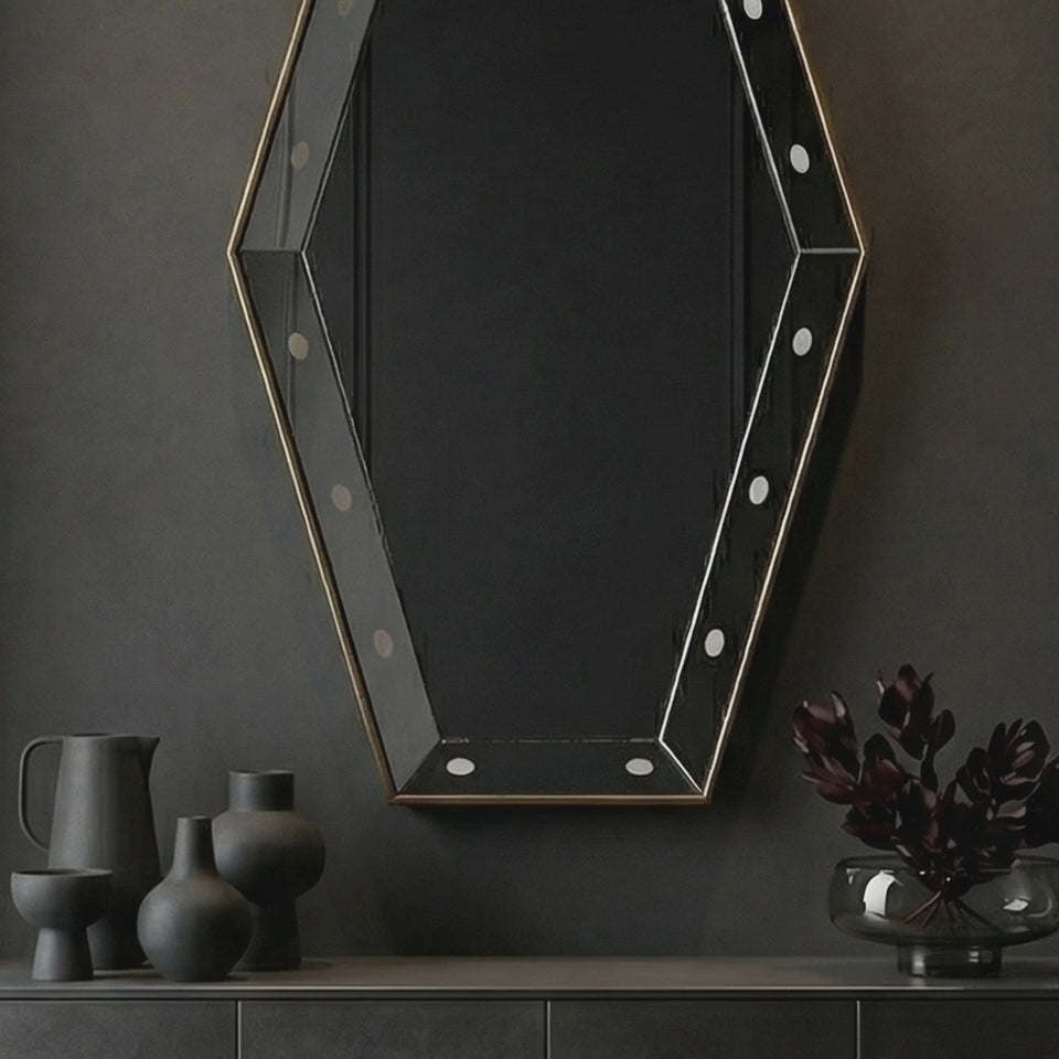 Short product video of Ambella Home Key Hole Mirror in antique gold, 30W x 5D x 54H faceted geometric wall mirror above a dark credenza in a luxury hallway