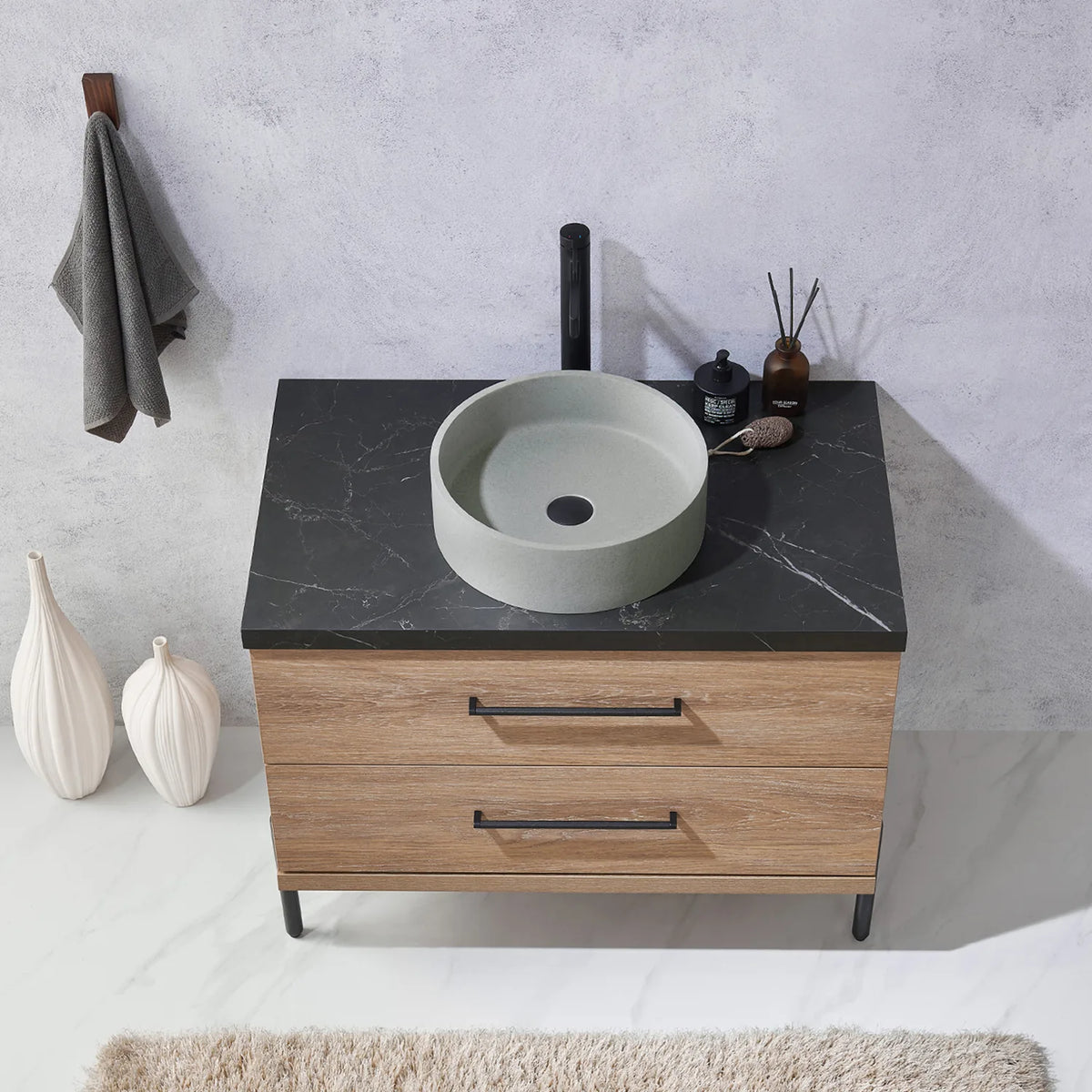 Stone top, a circular concrete vessel and the bar handles of the drawers below, seen head-on