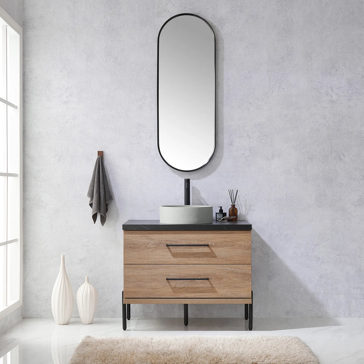 Towel on the wall hook and the oval mirror over the oak vanity in a bathroom