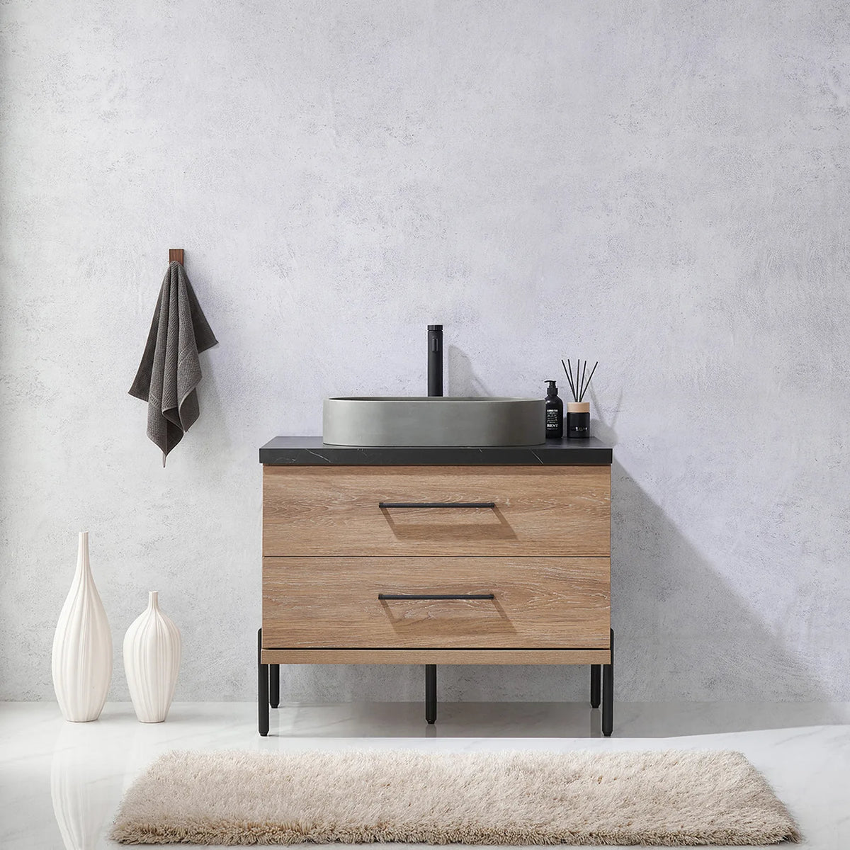 Pale plaster wall, white vases and a hanging towel behind the oak vanity on black legs