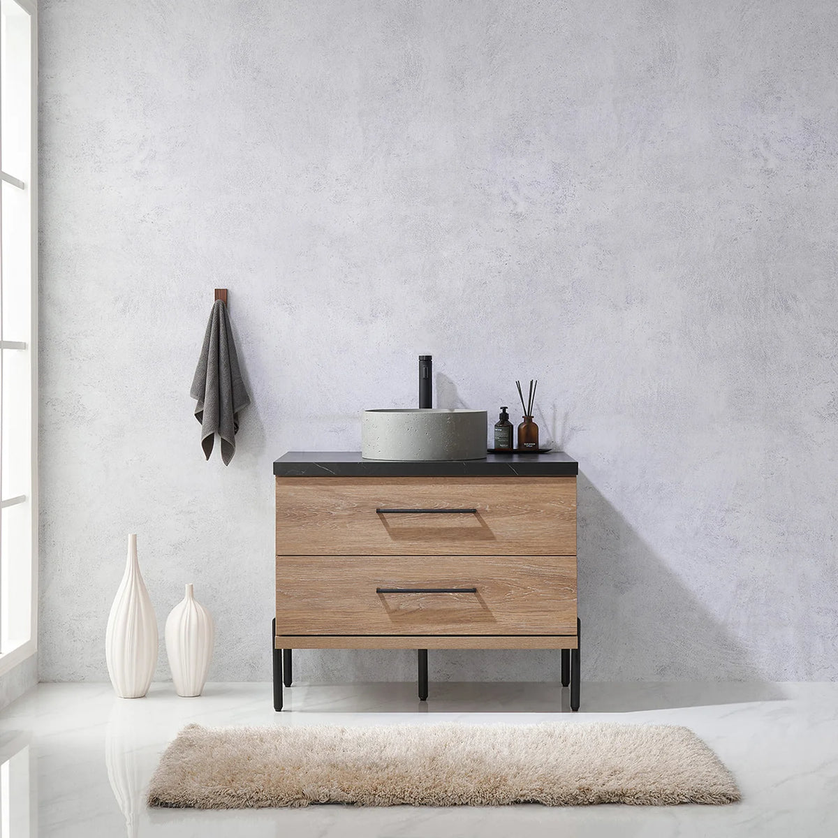 Pale plaster wall, white vases and a hanging towel behind the oak vanity on black legs