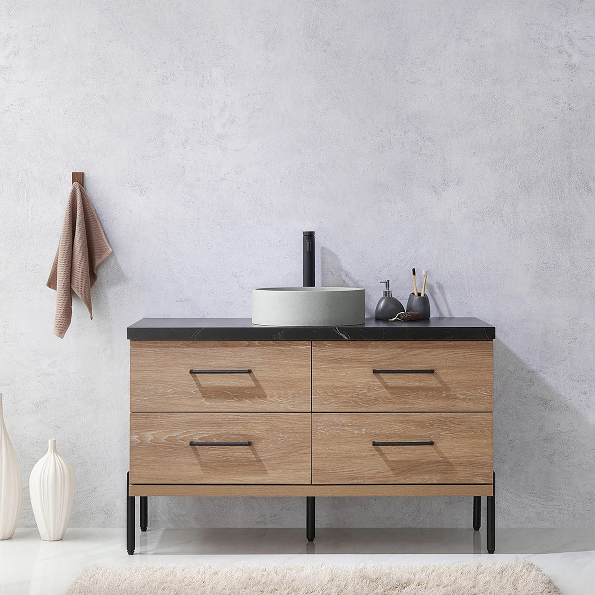 Pale plaster wall, white vases and a hanging towel behind the oak vanity on black legs