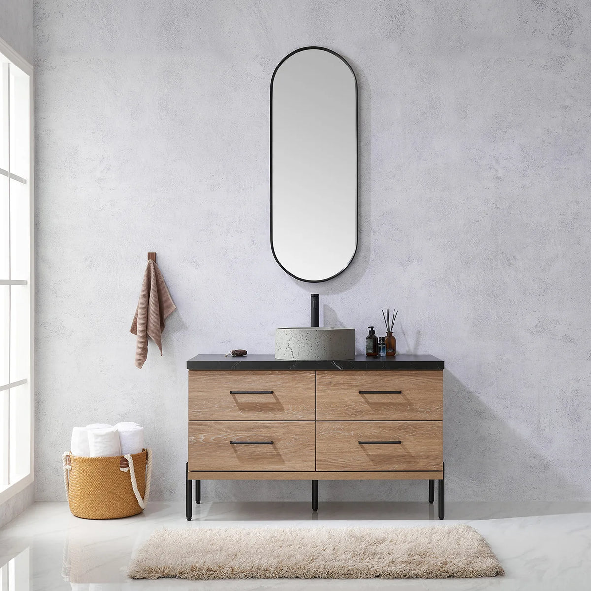 Towel on the wall hook and the oval mirror over the oak vanity in a bathroom