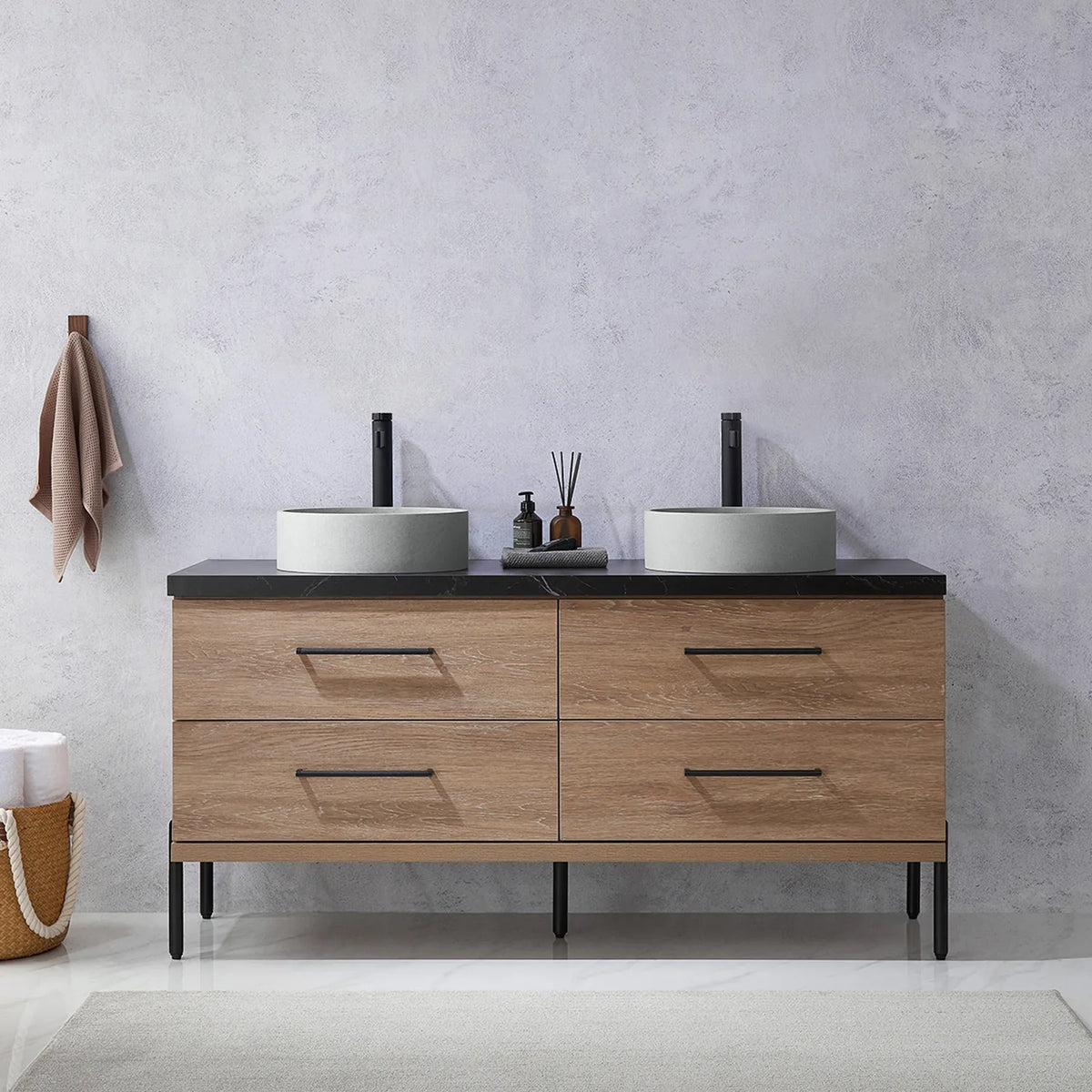 Pale plaster wall, white vases and a hanging towel behind the oak vanity on black legs