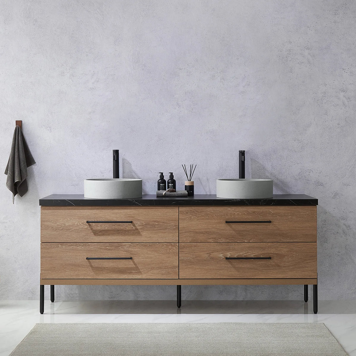 Pale plaster wall, white vases and a hanging towel behind the oak vanity on black legs