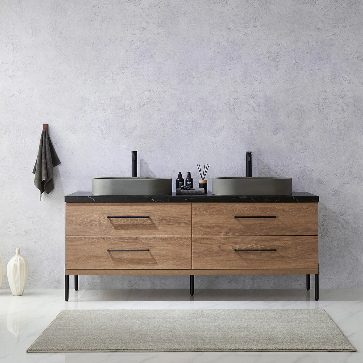 Pale plaster wall, white vases and a hanging towel behind the oak vanity on black legs